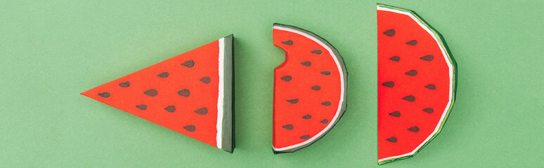 panoramic shot of handmade paper red watermelon slices isolated on green