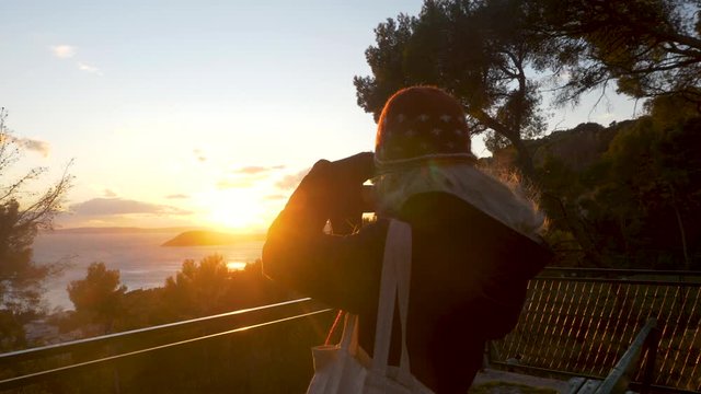 Slowmotion shot of blond womand looking at the sunset.