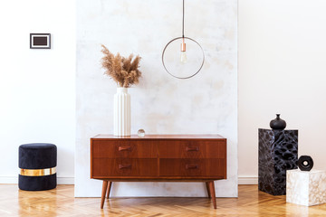 Stylish and eclectic interior of living room with design retro cabinet, black pouf, marble pedestals and elegant accessories. Abstract background wall. Mockup photo frame. Minimalistic home decor. 