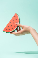 cropped view of young woman holding paper watermelon with seeds on turquoise