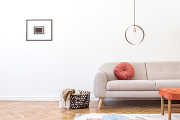 Stylish minimalistic living room with design grey sofa,  geometric lamp, retro footrest, basket...