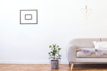 Stylish minimalistic living room with design grey sofa, triangle lamp, elegant accessories and plant in cement pot on the parquet. Mock up posters frame on the white walls. Minimalistic home decor. 