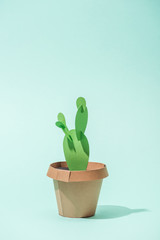 handmade green paper cactus in flower pot on turquoise with copy space