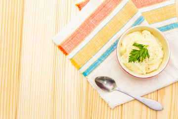 Warm mashed potatoes in a ceramic bowl with fresh parsley. On a vintage linen napkin on a stone background, copy space, top view, close up.