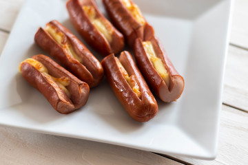 Roasted sausage with yellow cheese over white wooden background
