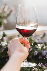 A woman's hand holding a glass of red wine