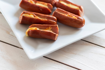 Roasted sausage with yellow cheese over white wooden background