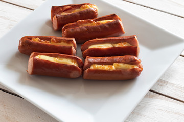 Roasted sausage with yellow cheese over white wooden background