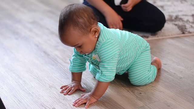 Smiling baby preparing to crawl but watches tv