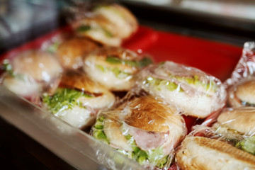 Close up of delicious fresh sandwiches in foil ready for sale. Bakehouse interior.