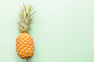 Fresh pineapple lying on green background. Top view. Flat lay concept. Place for text