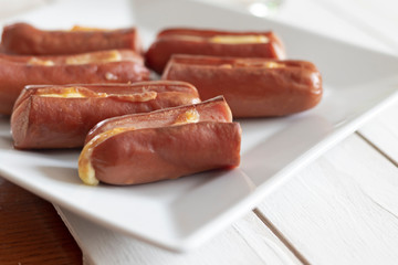 Roasted sausage with yellow cheese over white wooden background
