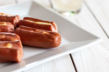 Roasted sausage with yellow cheese over white wooden background