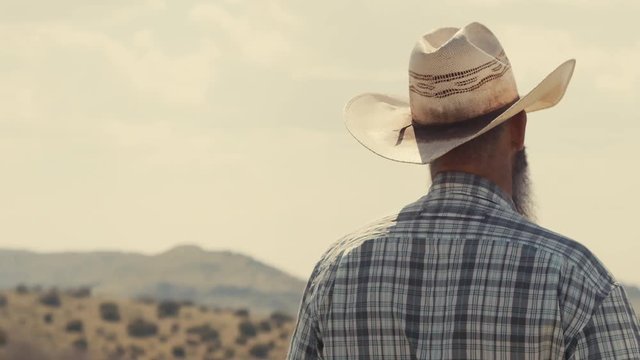 Close up of a cowboy overlooking a valley in Texas with mountain range on the horizon.