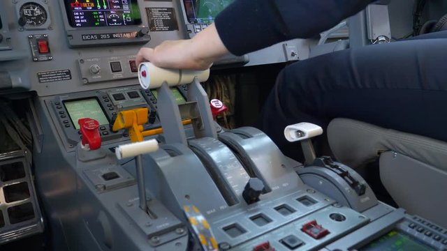 Close Up of Throttle Unit in Cockpit of Regional Airplane Taking Off at Airport With Hand of Pilot and Other Instruments.
