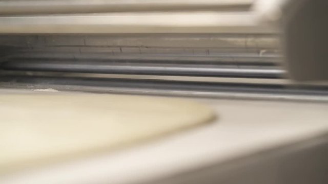 A close-up demonstration video of the viennoiserie dough rolling out by the reversible countertop dough sheeter. Industrial croissant production concept
