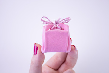 Pink gift box with ribbon for decorations in hand. Festive gift to a girl or woman