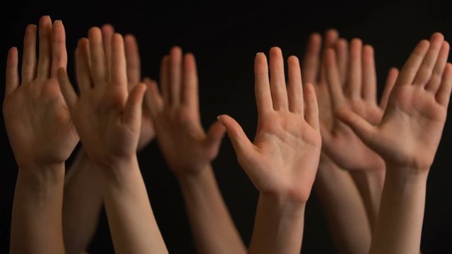 Raising hands on black background.