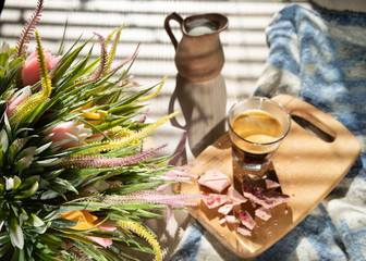 in bed, black coffee in a glass cup, a milk jug, crumbled pink chocolate on a blackboard and a bouquet of wildflowers, low light, horizontal frame