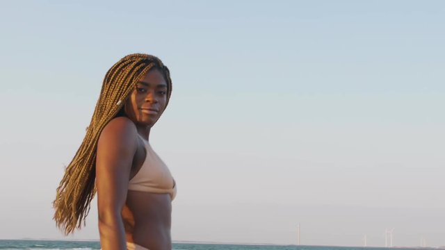African swimwear model with braids having fun posing at the beach during a sunset