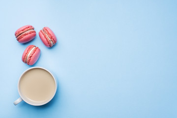 Concept morning Breakfast. Cup of coffee macaroon cookies on blue pastel background. Flat lay style.