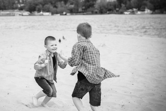 Kids boys playing on a beach near river with water and sand felling happy	 