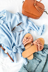 Feminine summer fashion composition with blouse, slippers, purse, sunglasses, watch, jean shorts on...