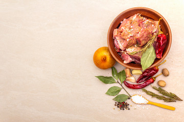 Raw pork shoulder. Spices, dry herbs, garlic, rosemary, bay leaf, hot and mix pepper, nutmeg, onion, salt. Ingredients for marinating meat. Rustic ceramic bowl on stone background top view copy space