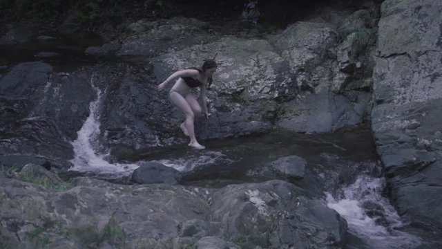 SLOW MOTION: girl crosses a stream that runs to Mango Waterfall in Adjuntas, Puerto Rico