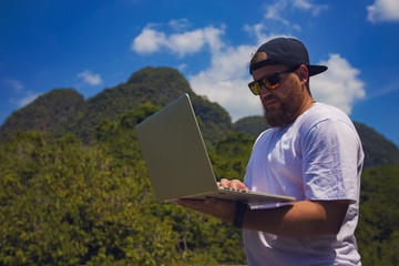 Young stylish bearded blogger working on vacation in the mountains.