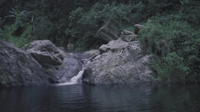 SLOW MOTION: girl climbs down a rocky structure that's a part of Mango Waterfall in Adjuntas, Puerto Rico.