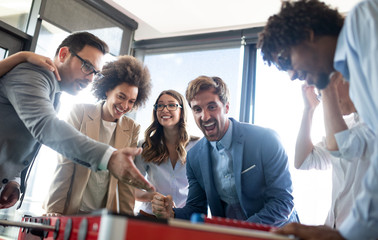 Multicultural business people celebrating win while playing table football