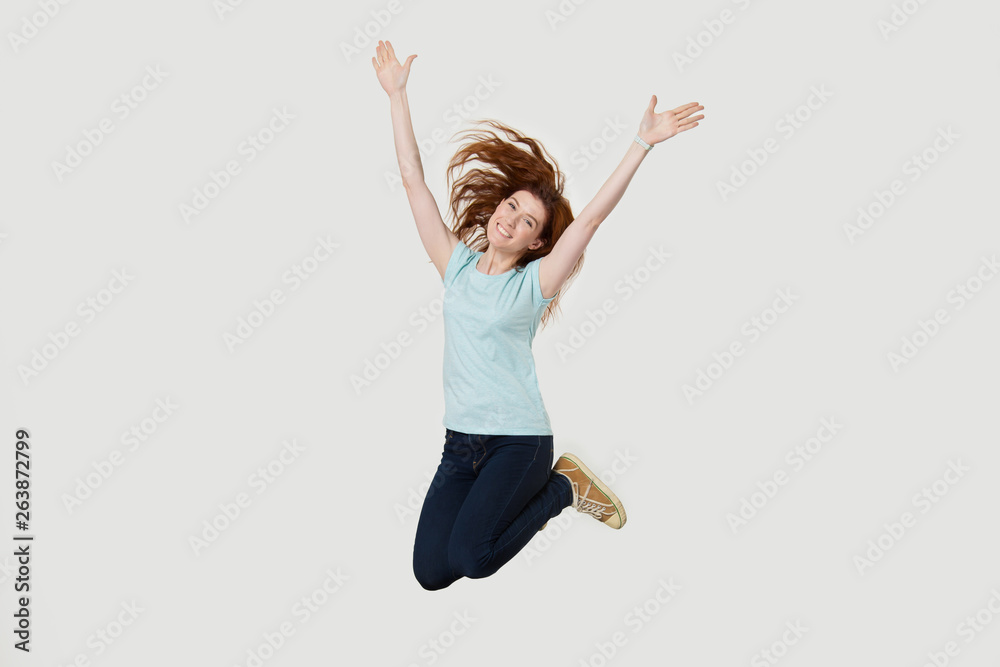 Wall mural excited redhead girl have fun jumping with hands up