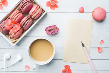 Cup of coffee, macaroon cookies in a box, flowers and a notebook on a white background. copy space. concept beautiful Breakfast. flat lay