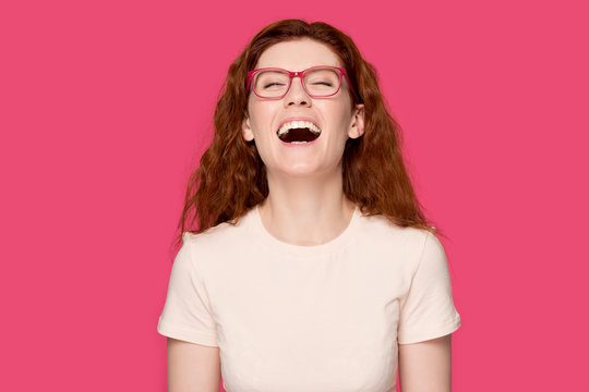Happy red-haired girl in glasses laughing at joke