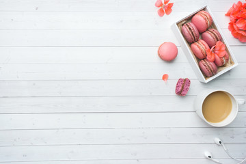 Cup of coffee, macaroon cookies in a box, flowers on a white background. copy space. concept beautiful Breakfast. flat lay