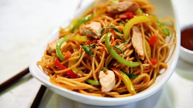 Chicken Hakka/Schezwan noodles footage / video, served in a bowl with chopsticks. selective focus