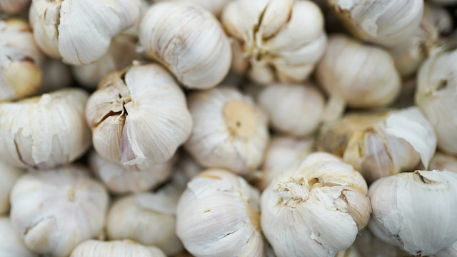 garlic pile texture. Fresh garlic on market table close-up photo. Vitamin healthy food spice image.