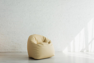sunlight near beige bean bag chair near brick wall in modern home