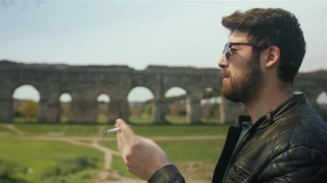 Man is smoking a cigarette while waiting in the park.