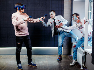 Concept, a man playing video games about zombies, wearing virtual reality glasses. Grim zombies.