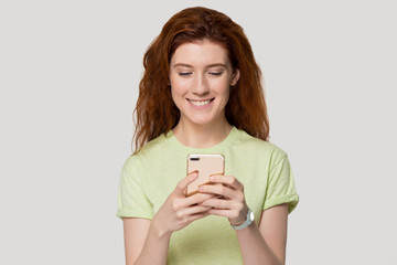 Smiling redhead girl happy receive pleasant message on smartphone