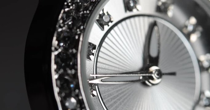 Angled, closeup shot of a silver, diamond-studded watch at 12:40.