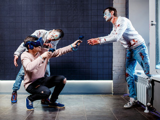 Concept, a man playing video games about zombies, wearing virtual reality glasses. Grim zombies.