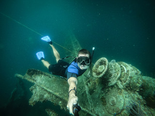 Free diver taking selfie with sunken ship on background