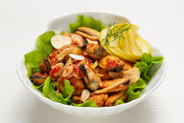 a portion of mussel salad, in a spicy sauce with garlic, with lemon slices, decorated with greens, close-up