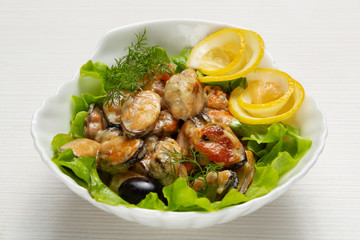 dish of mussels in a plate, with a delicate sauce, decorated with lemon and herbs, close-up shot