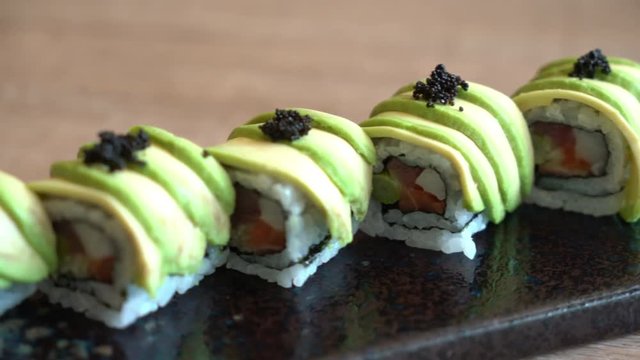 Close up of Japanese sushi, a type of raw fish, served with avocado on a platter.