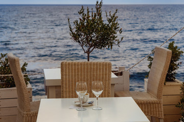 two glasses and a cup of coffee on the table of the beach cafe against the blue sea