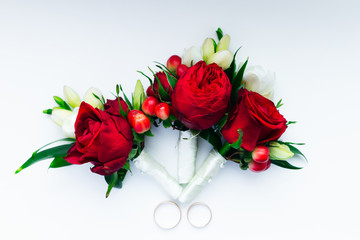 boutonniere and wedding rings on a white background. top view
